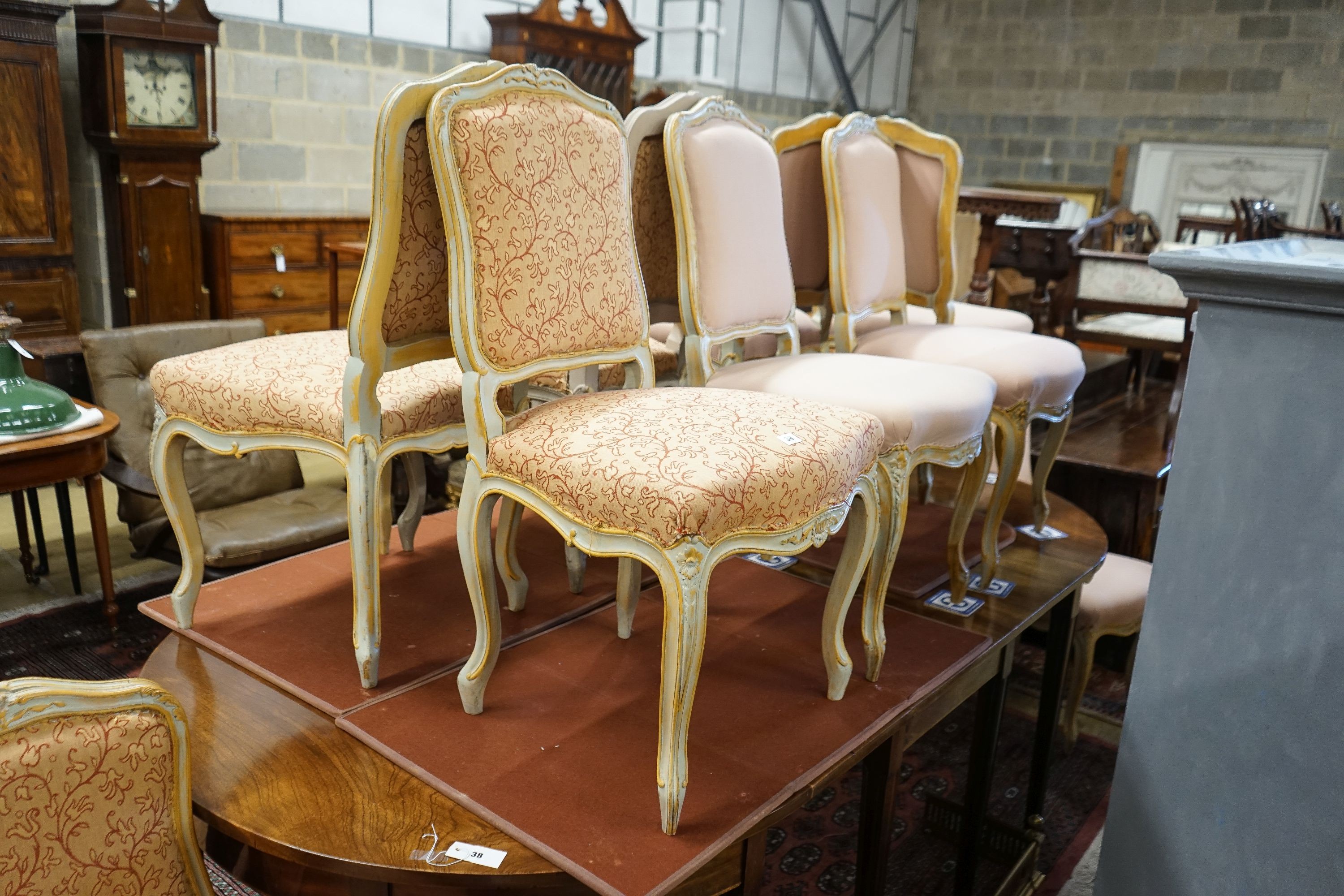 A set of fourteen French Louis XV style painted upholstered dining chairs with loose covers